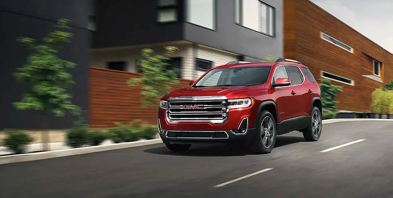 A red 2021 GMC Acadia driving down the road.